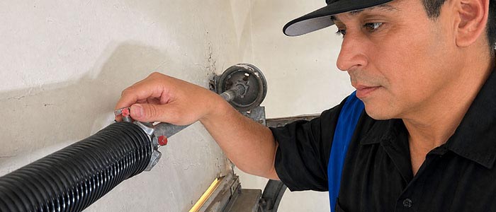 Garage door repair technician replacing a broken torsion spring in San Diego CA.