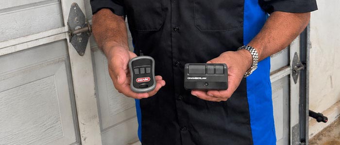 Garage door repair technician holding replacement garage door remotes, clickers San Diego CA