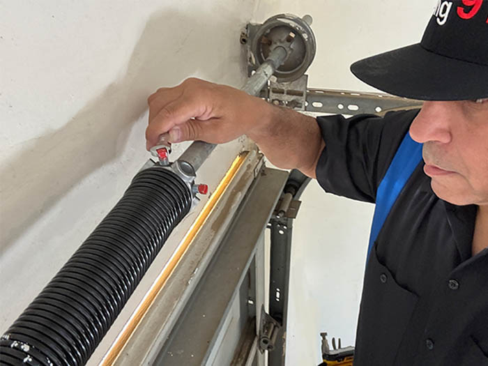 Garage door repair technician replacing a broken torsion spring in San Diego CA.