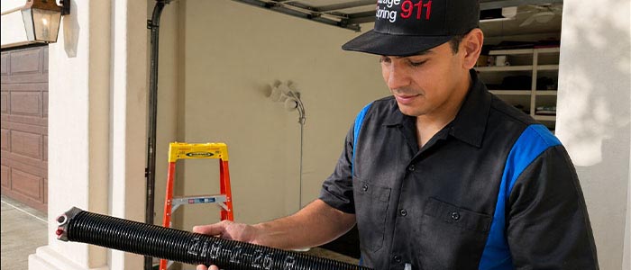 Garage door repair technician holding a broken torsion spring in San Diego CA.